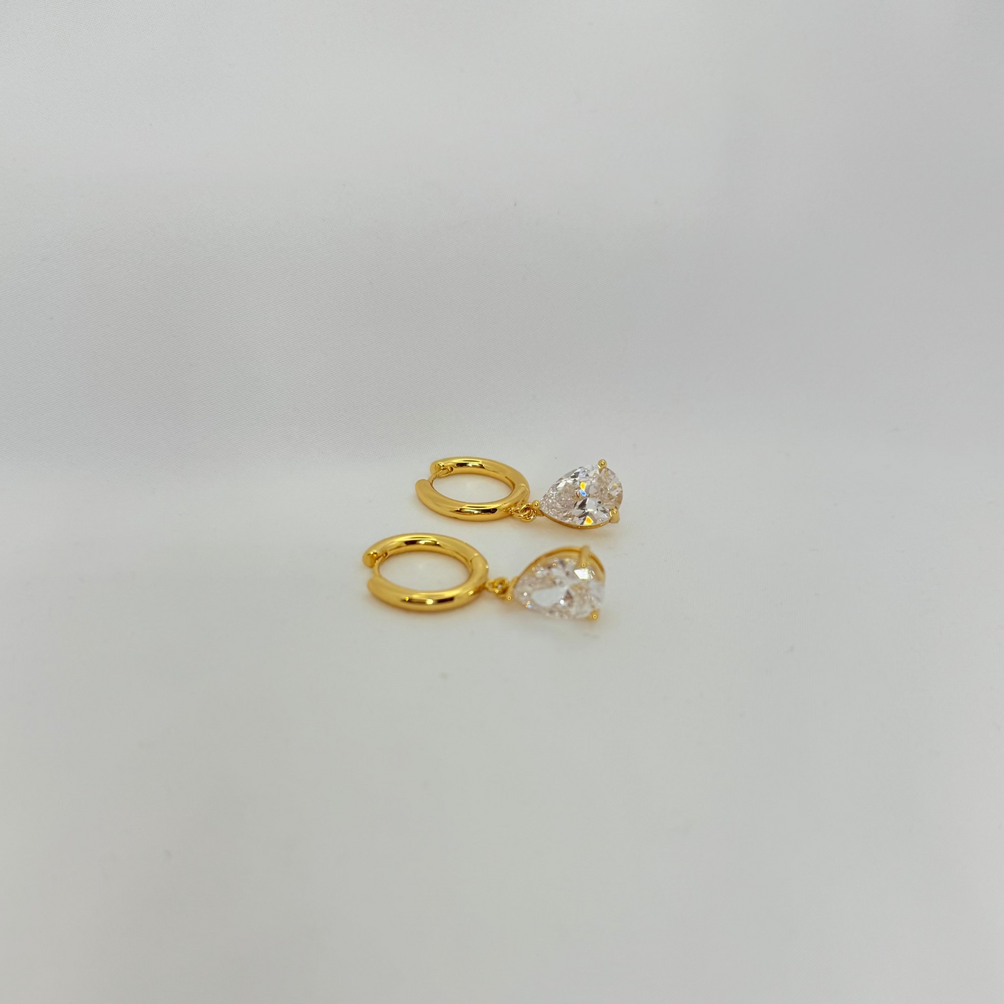Two gold rings with clear gemstones on a light gray background