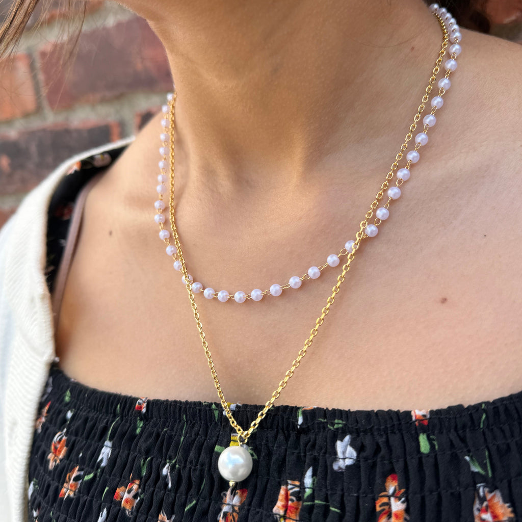 Pearl and gold body chain worn by a person with a floral dress.