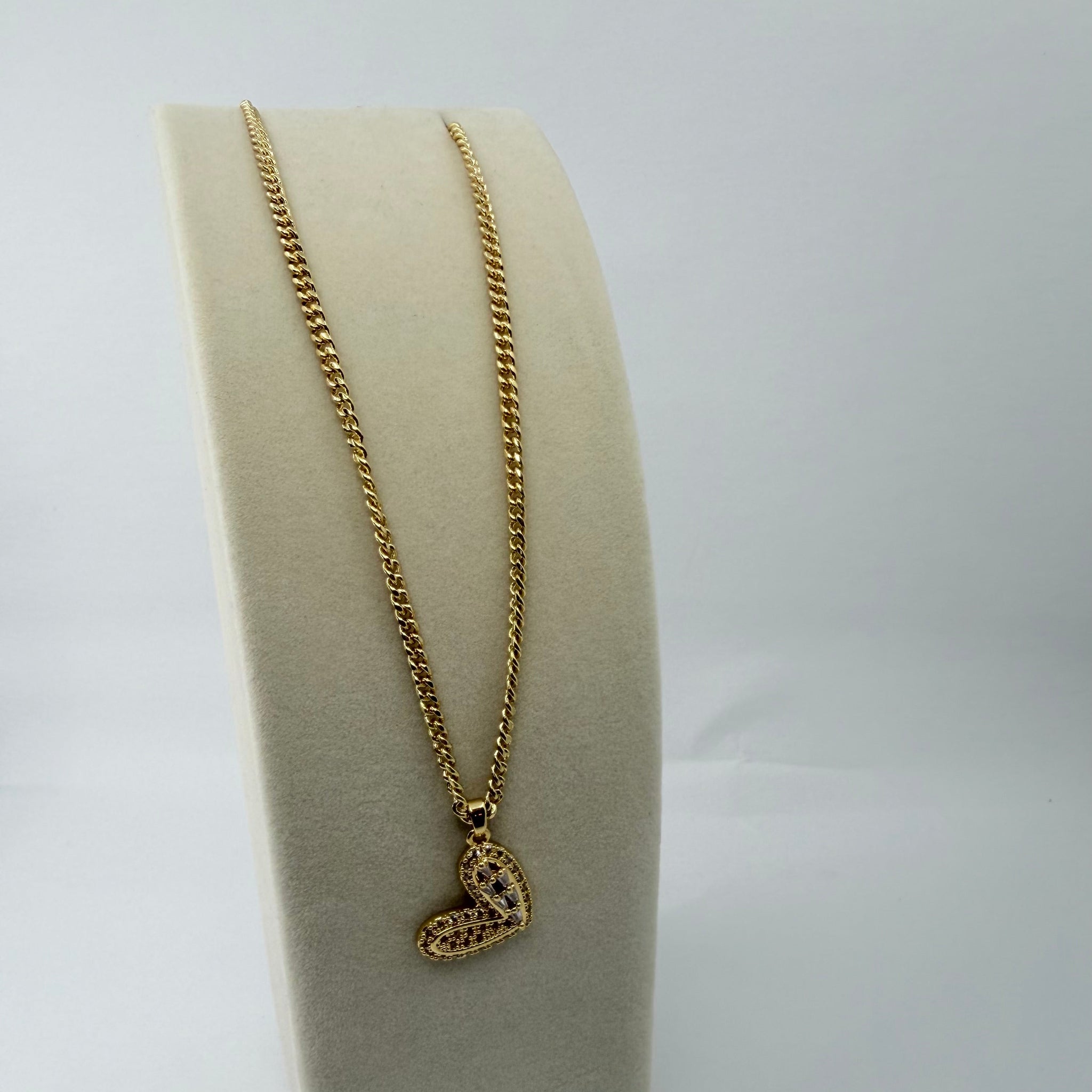 Gold necklace with a heart pendant on a white background