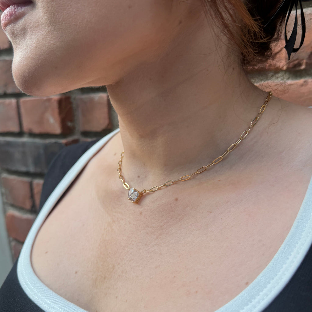 Close-up of a person wearing a gold necklace with a diamond pendant.