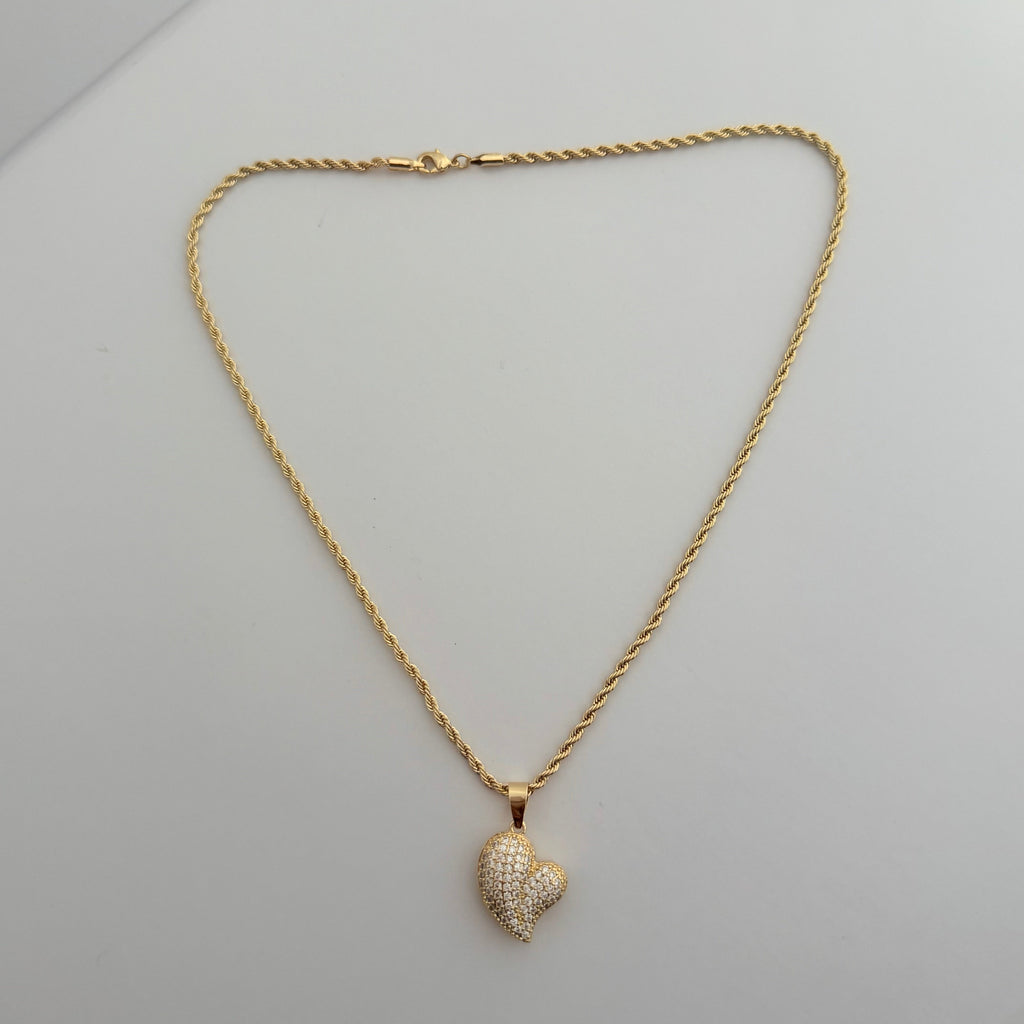 Gold necklace with a heart-shaped pendant on a light gray background