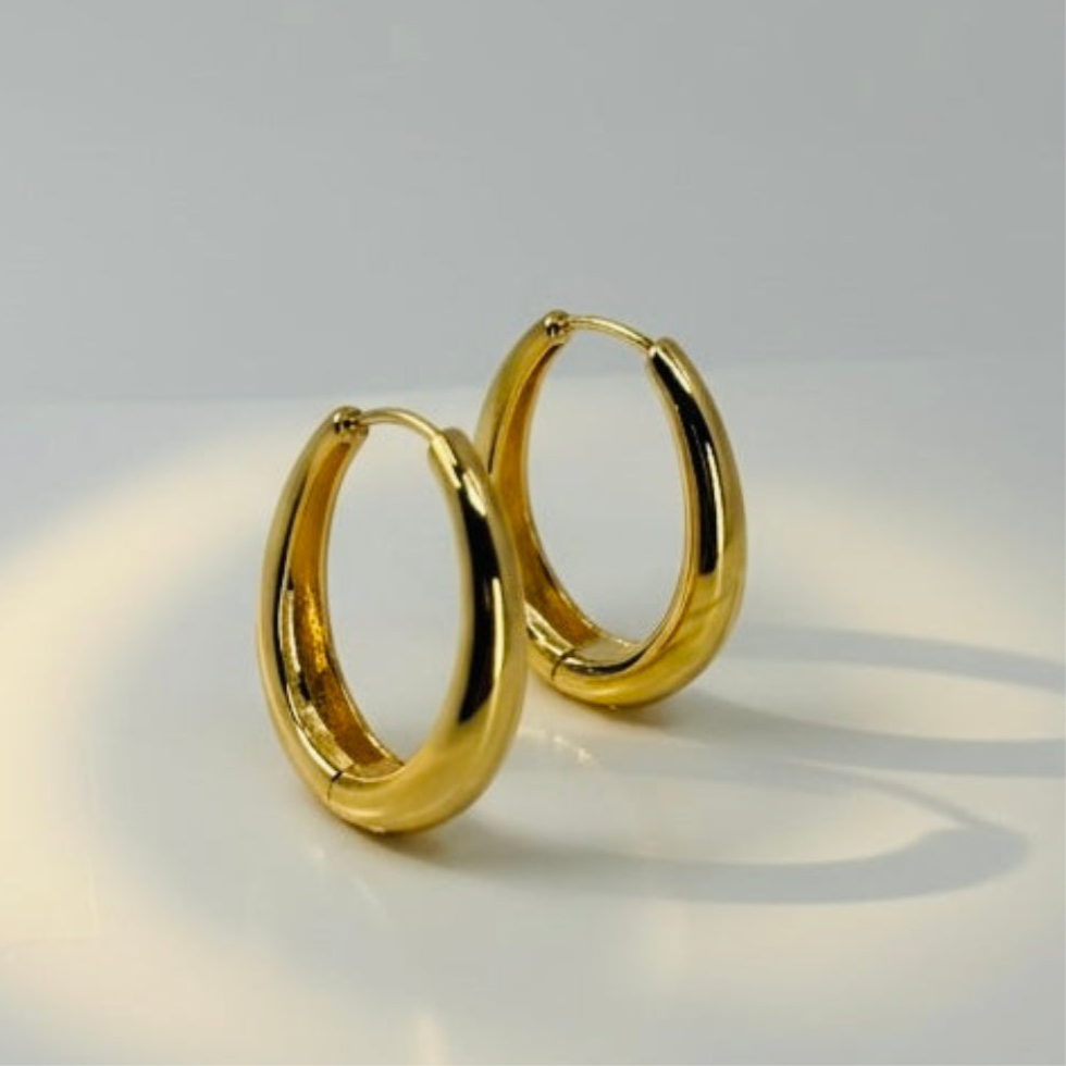 18K gold plated over brass, these polished oval hoop earrings feature a sleek, refined design with a smooth, high-shine finish.
