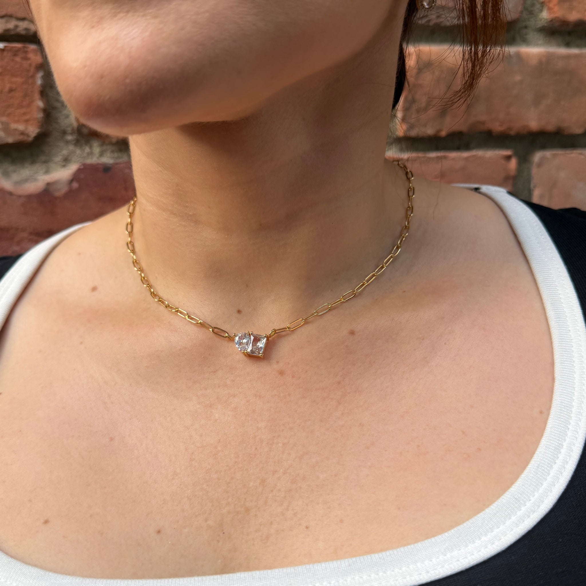 Gold bracelet with a diamond on a wrist against a brick wall background