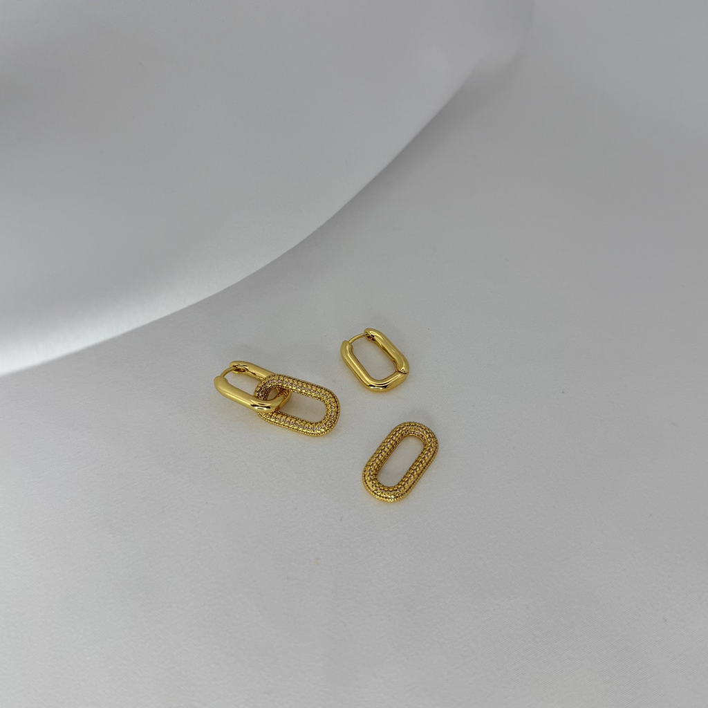 Two gold rectangular charms on a light gray surface