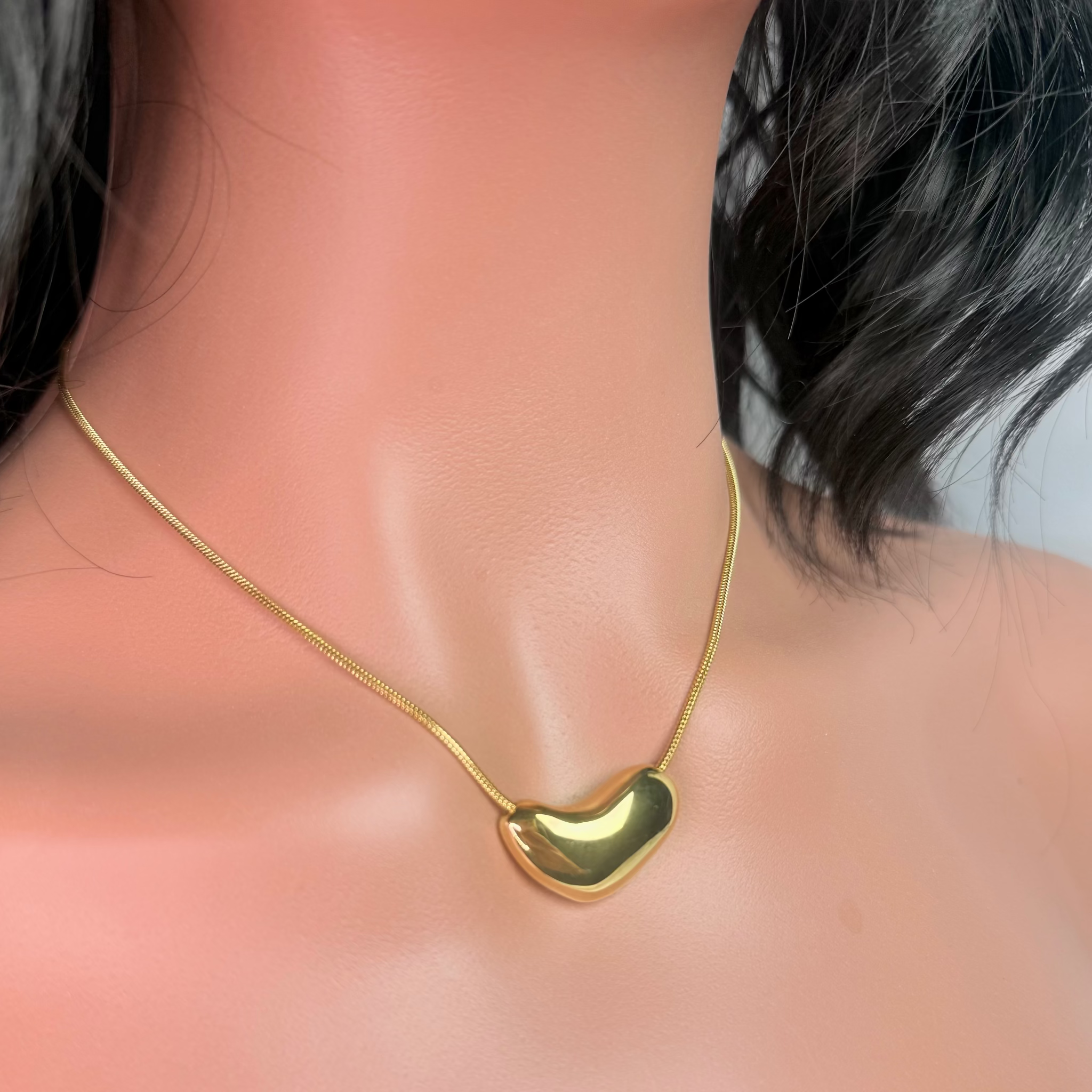 Gold necklace with a heart-shaped pendant on a mannequin