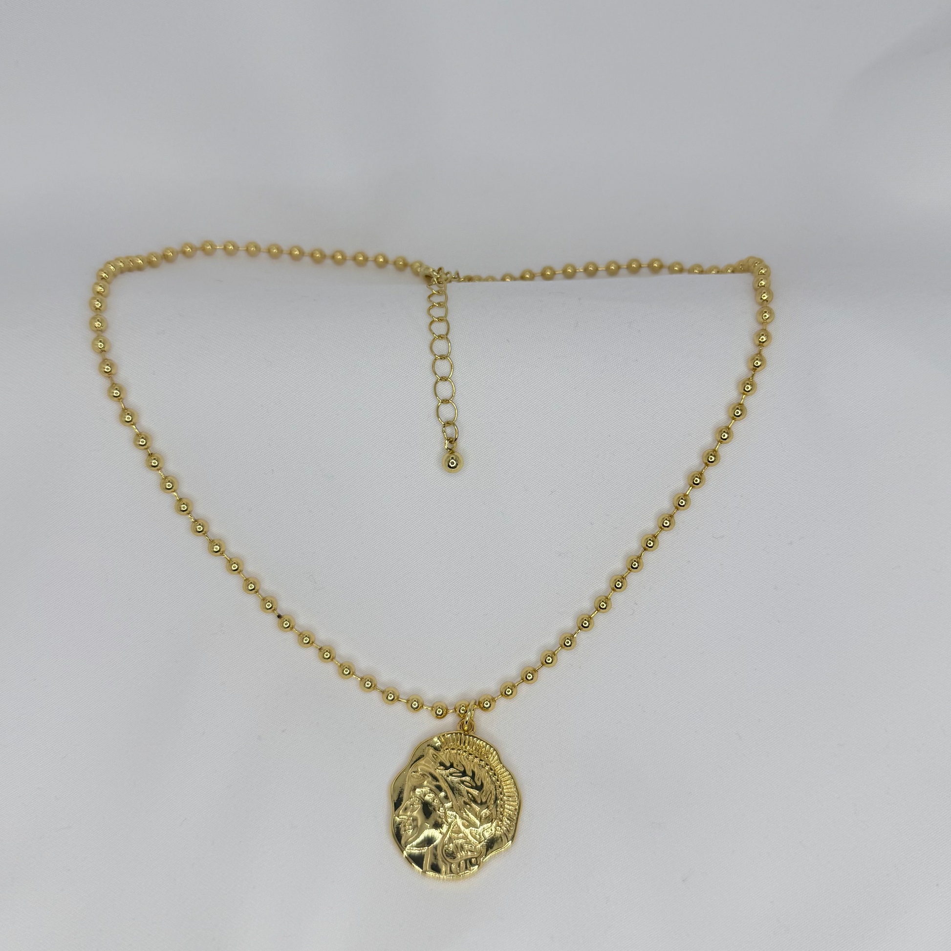 Gold necklace with a pendant on a white background