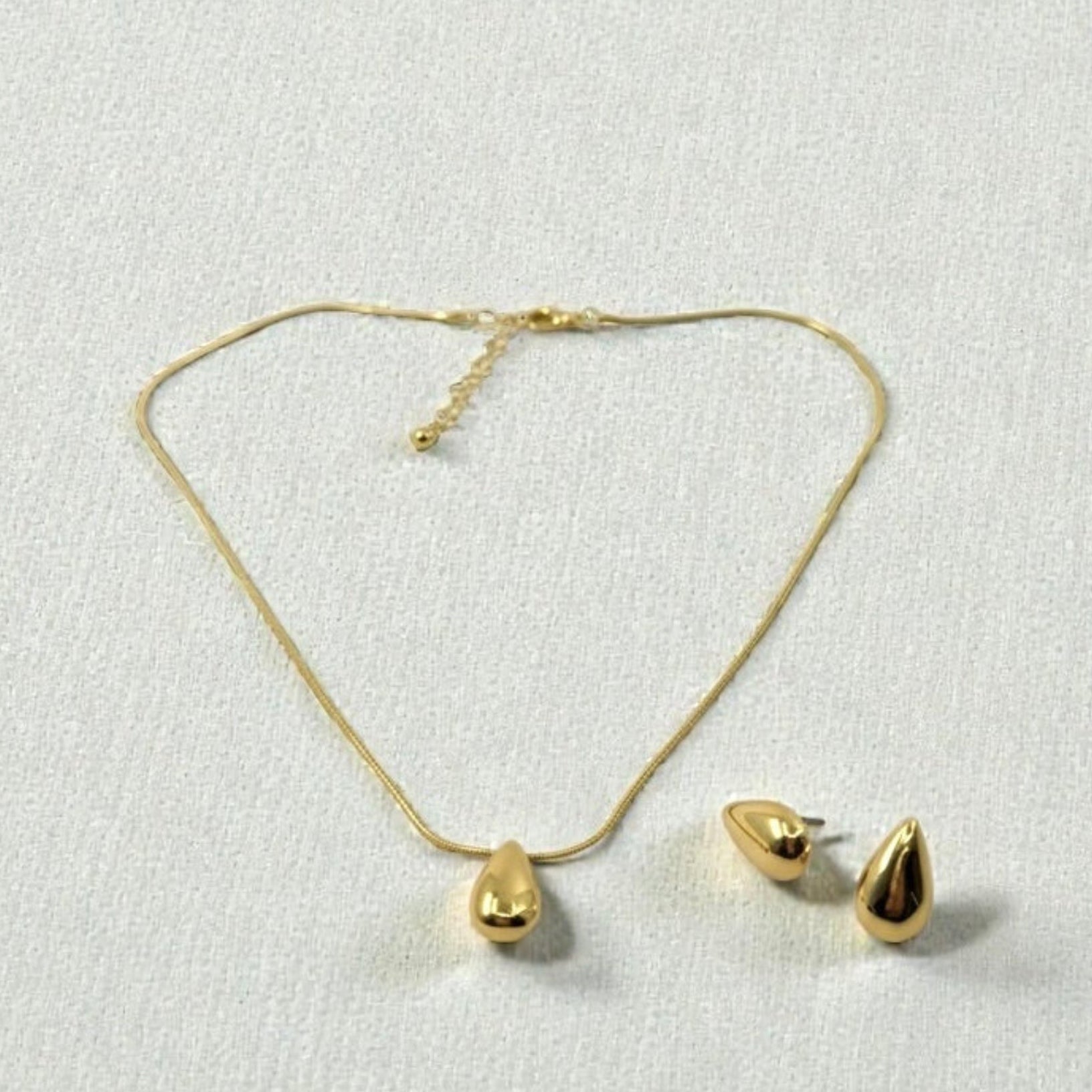 Gold necklace and earrings on a light gray background