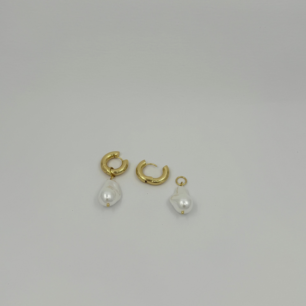 Gold hoop earrings with pearl drops on a light gray background