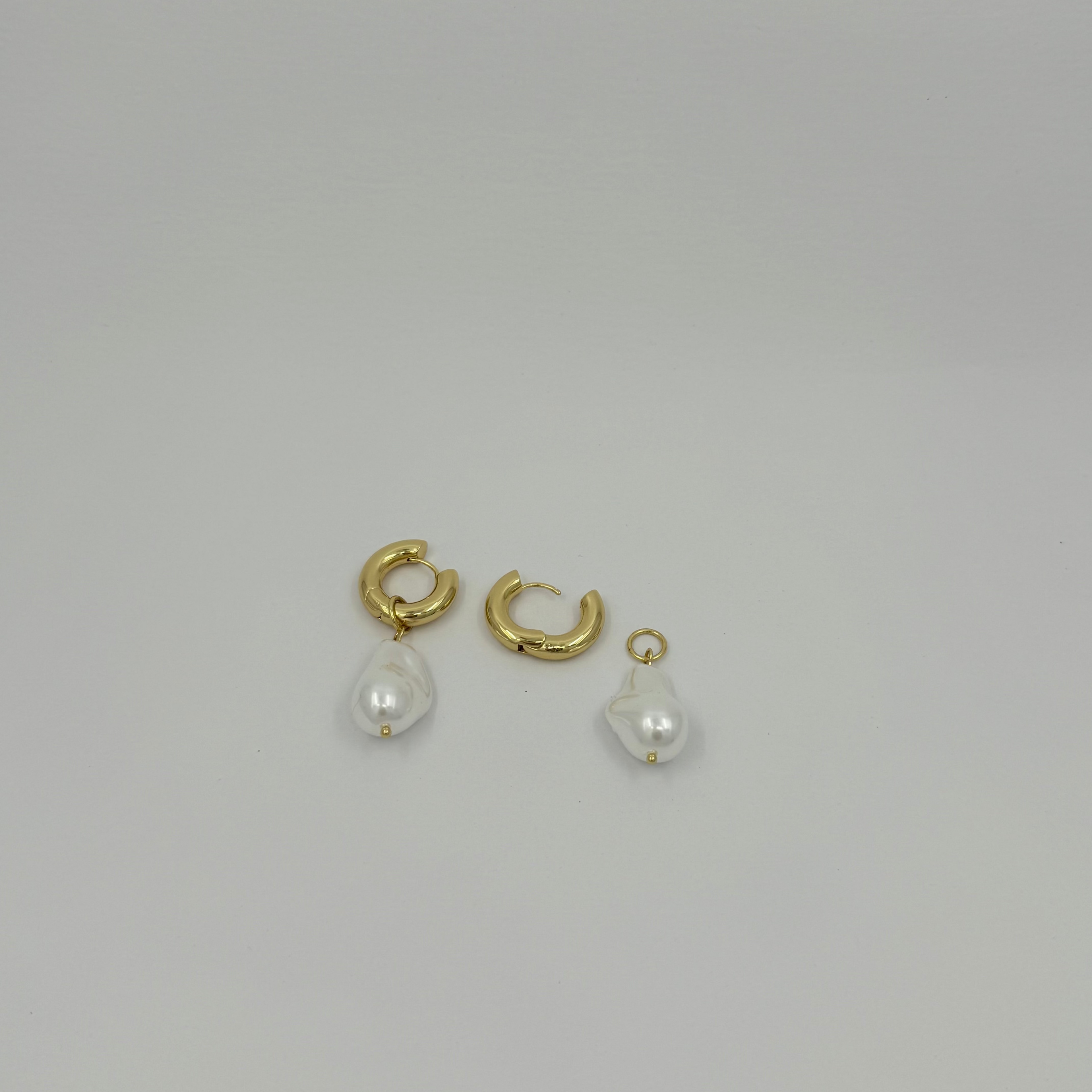 Gold hoop earrings with pearl drops on a light gray background