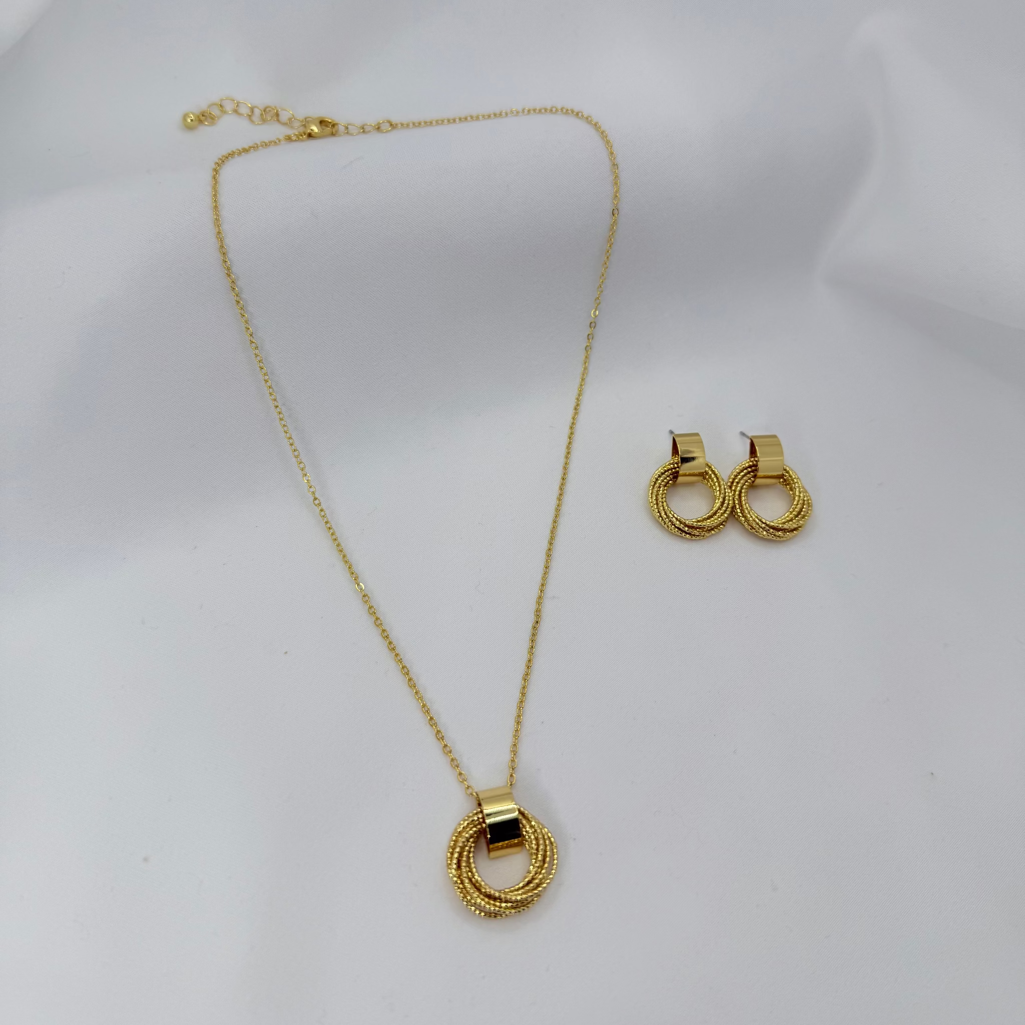 Gold necklace and earrings on a white mannequin bust