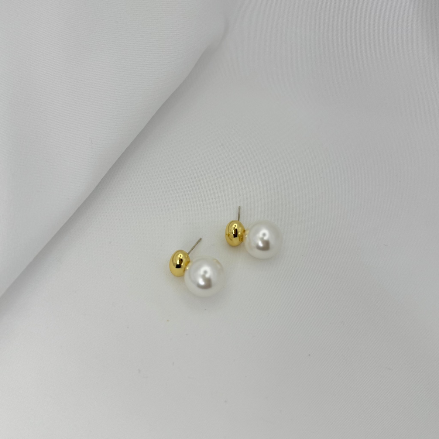 Pair of pearl earrings on a light gray background