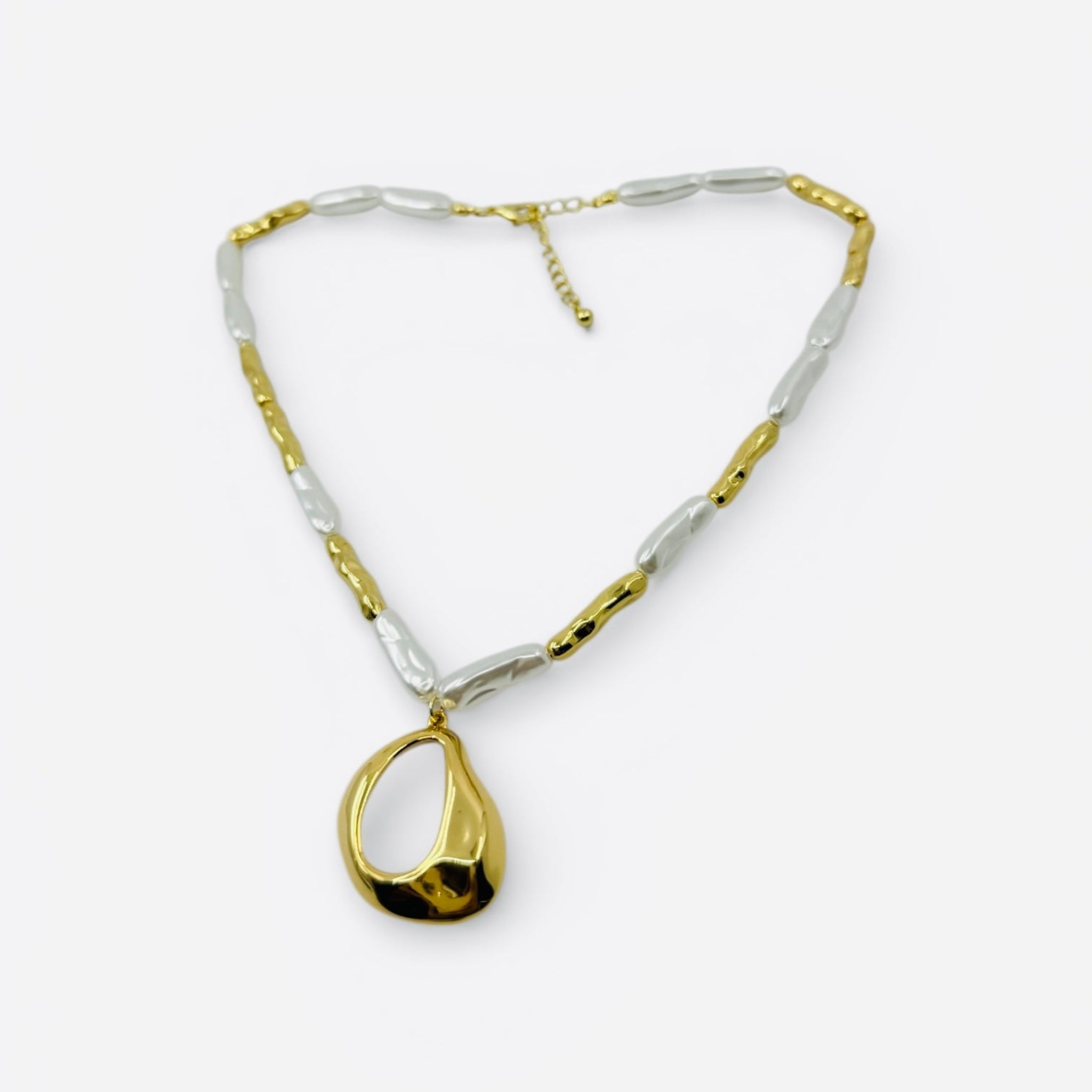 Gold and silver necklace with a teardrop pendant on a white background