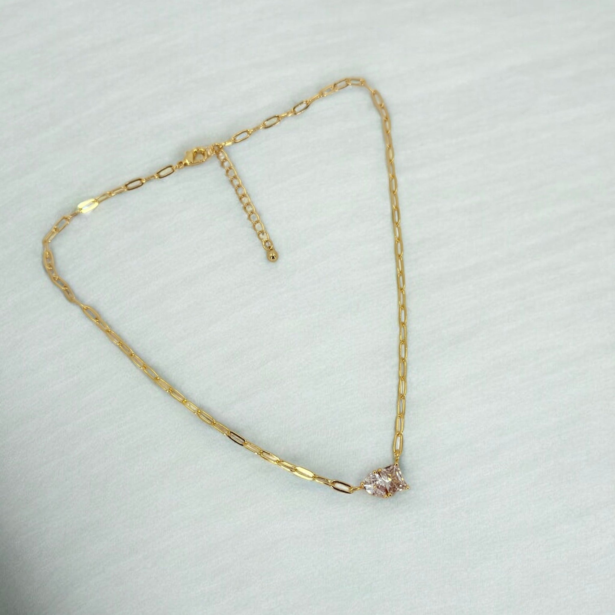 Gold necklace with a small pendant on a light gray background