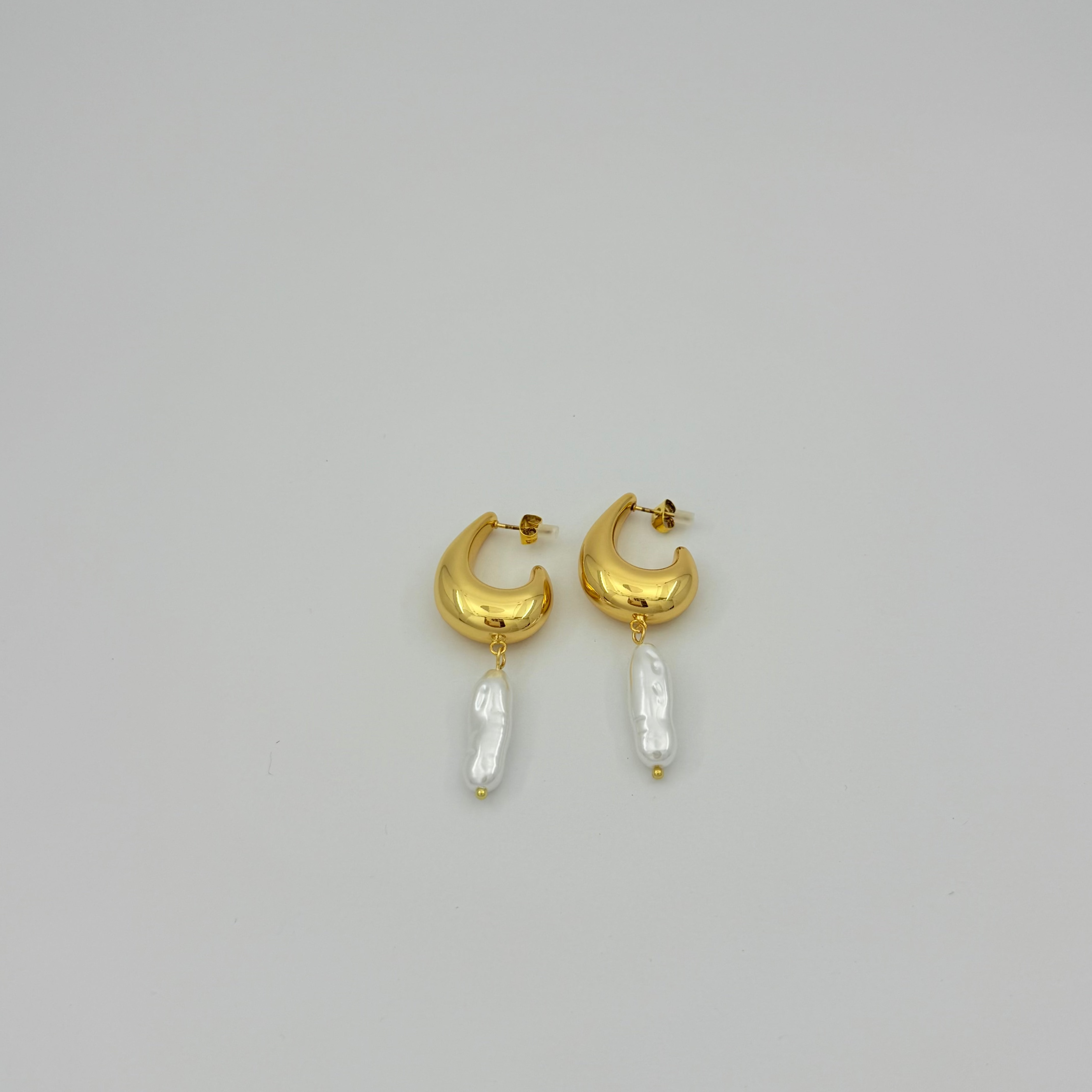 Gold hoop earrings with pearl-like beads on a light gray background