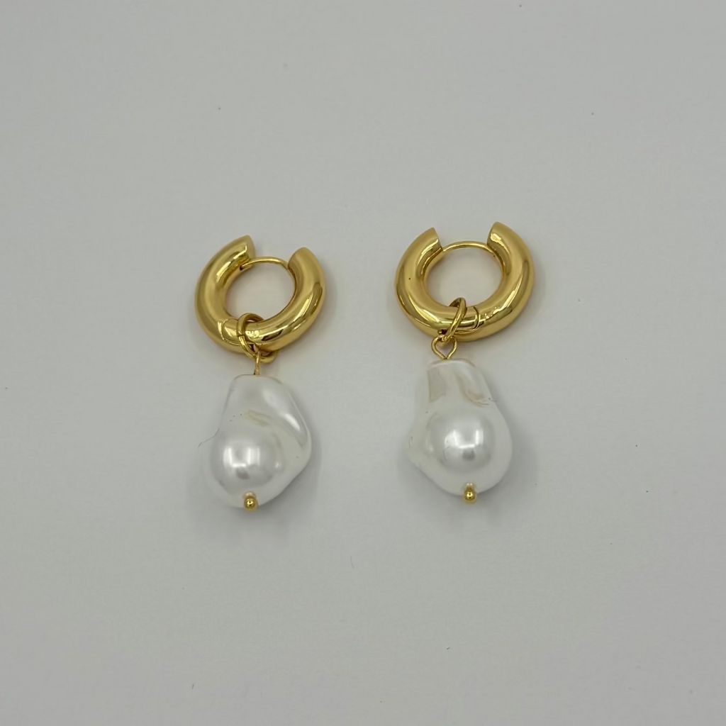 Gold hoop earrings with pearl drops on a light gray background