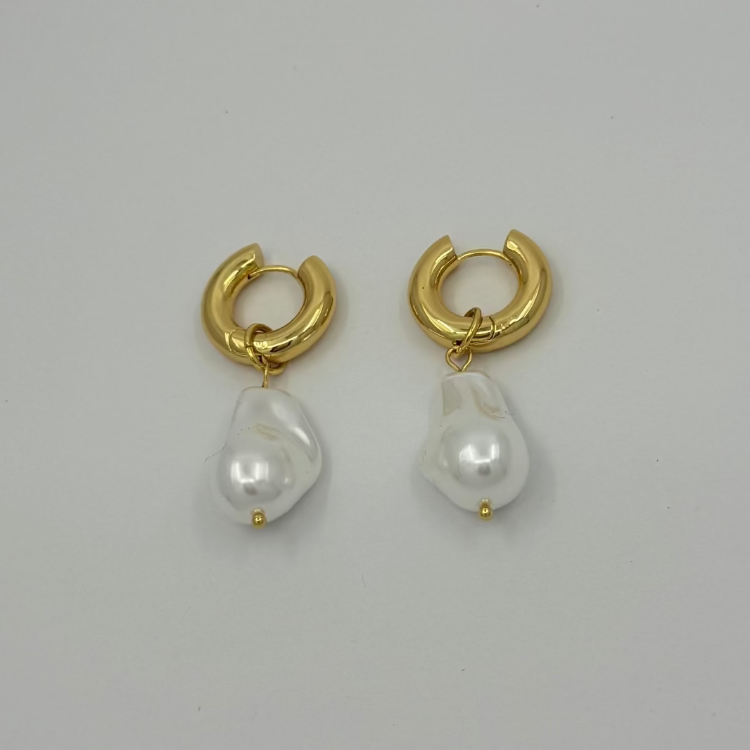 Gold hoop earrings with pearl drops on a light gray background