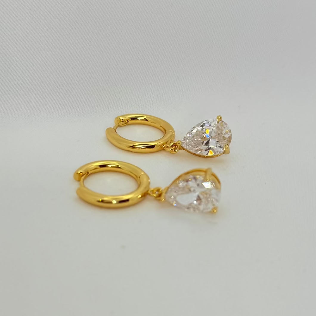 Two gold rings with clear gemstones on a light gray background