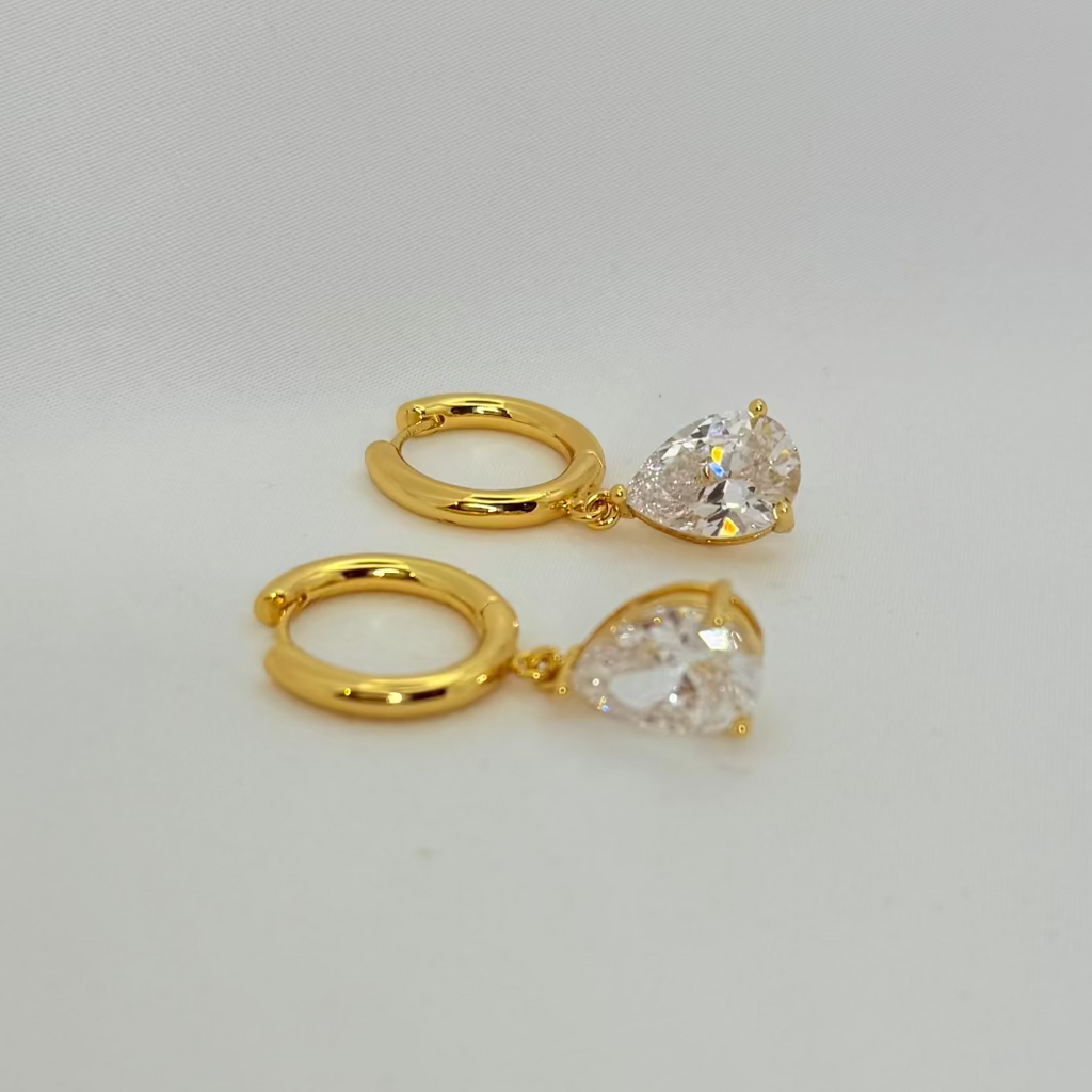 Two gold rings with clear gemstones on a light gray background