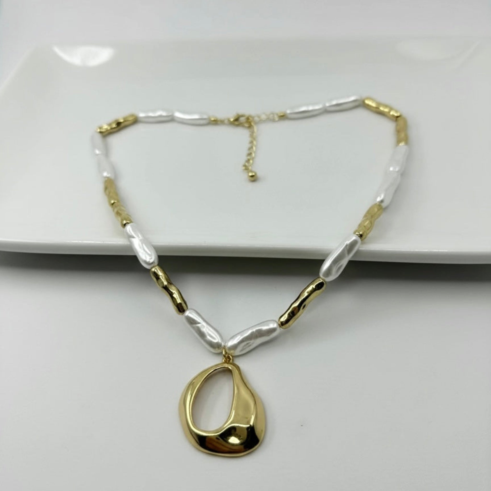 Gold necklace with a teardrop pendant on a white background