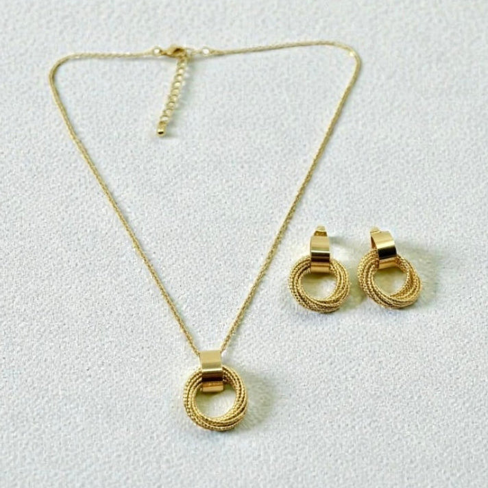 Gold necklace and earrings on a light gray background