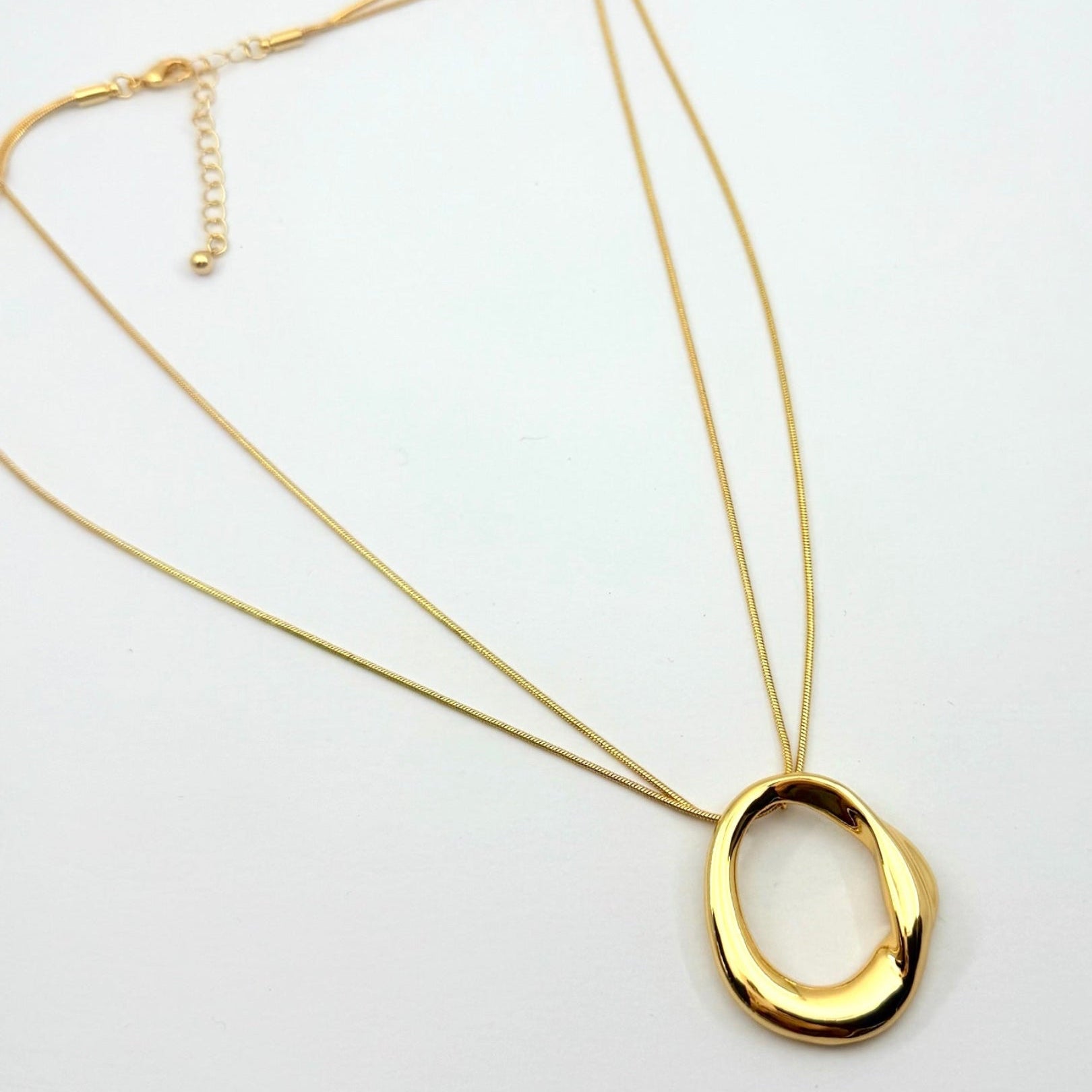Gold necklace with a large, oval pendant on a white background