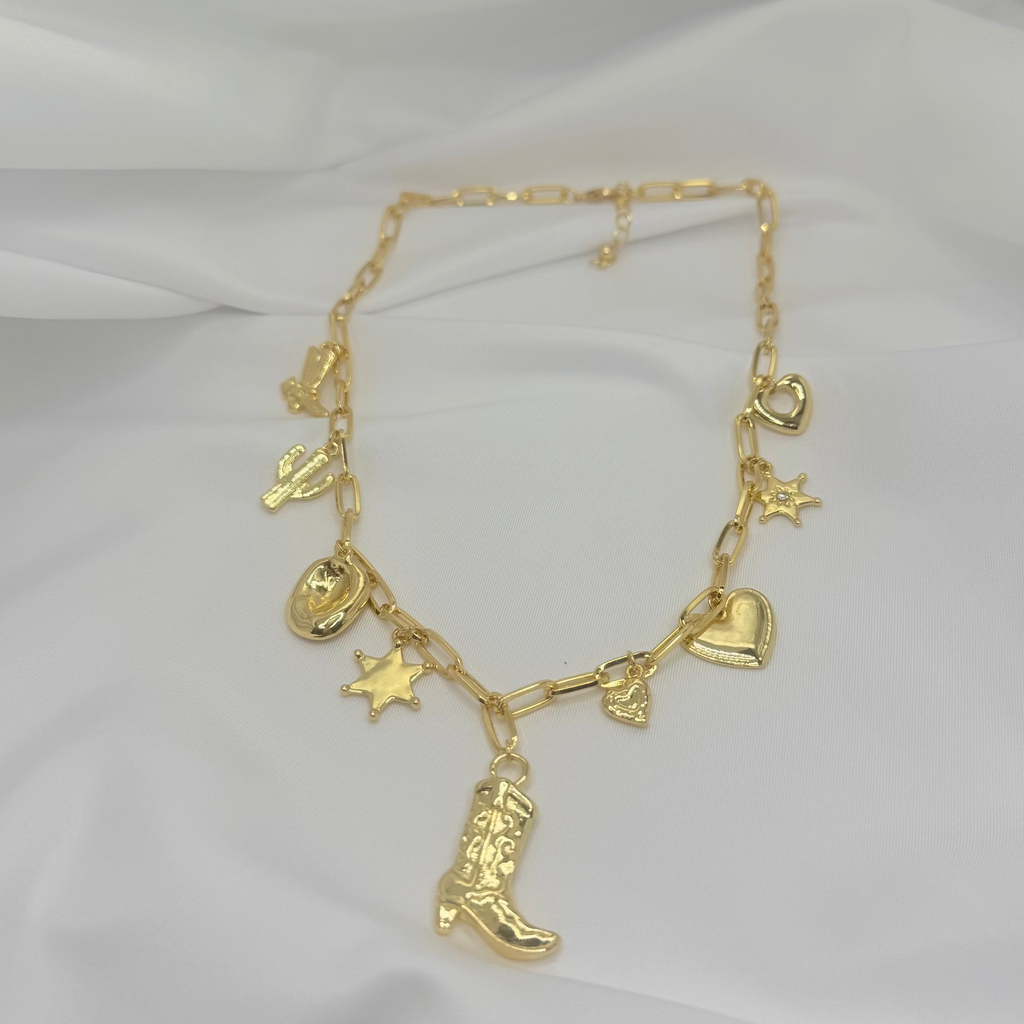 Gold necklace with various charms on a white fabric background