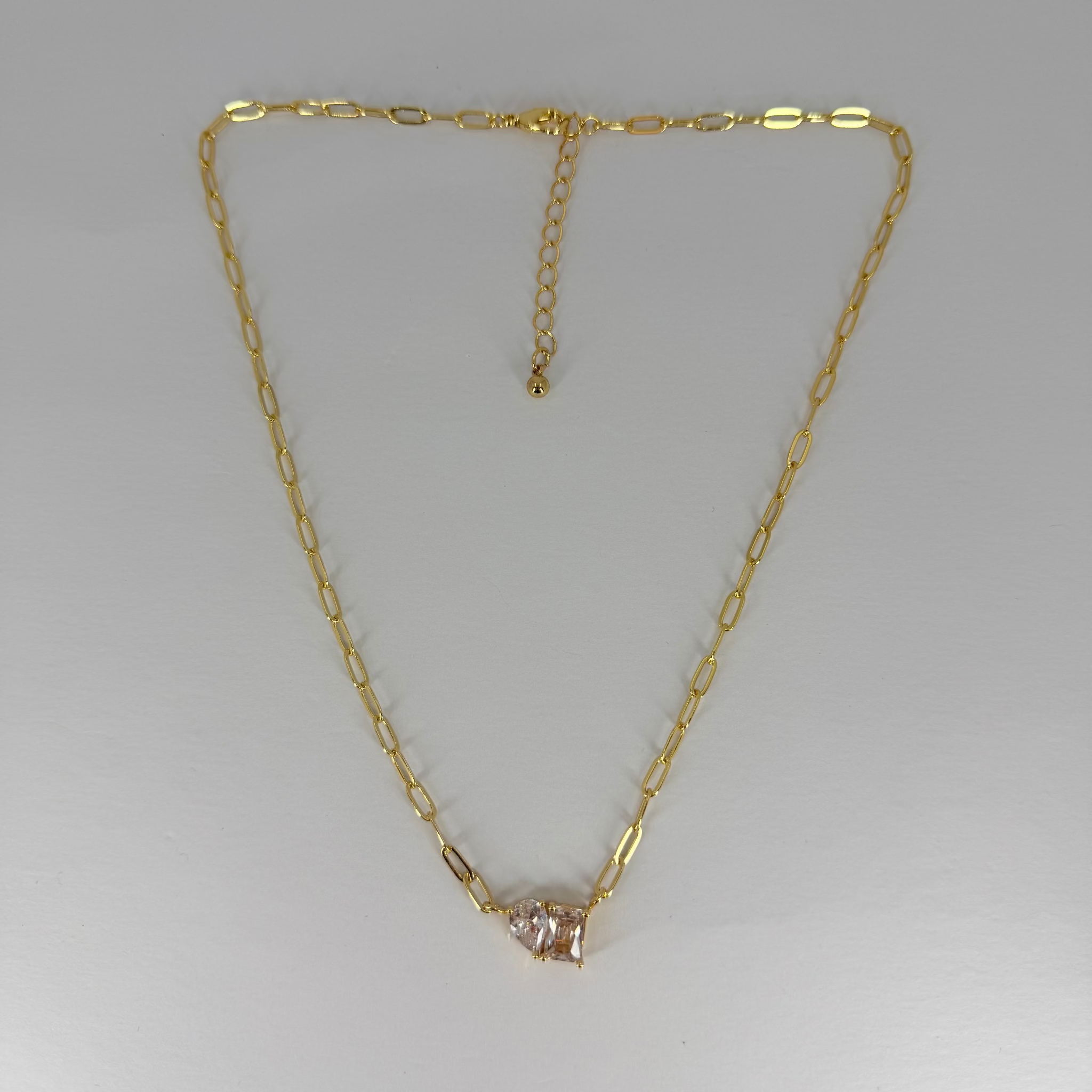 Gold necklace with a diamond pendant on a light gray background