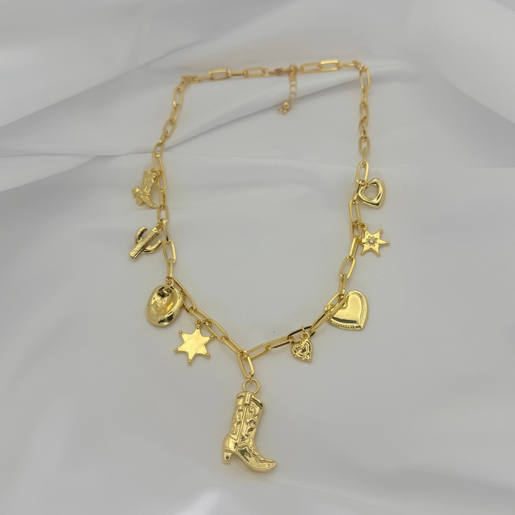 Gold necklace with various charms on a light gray background