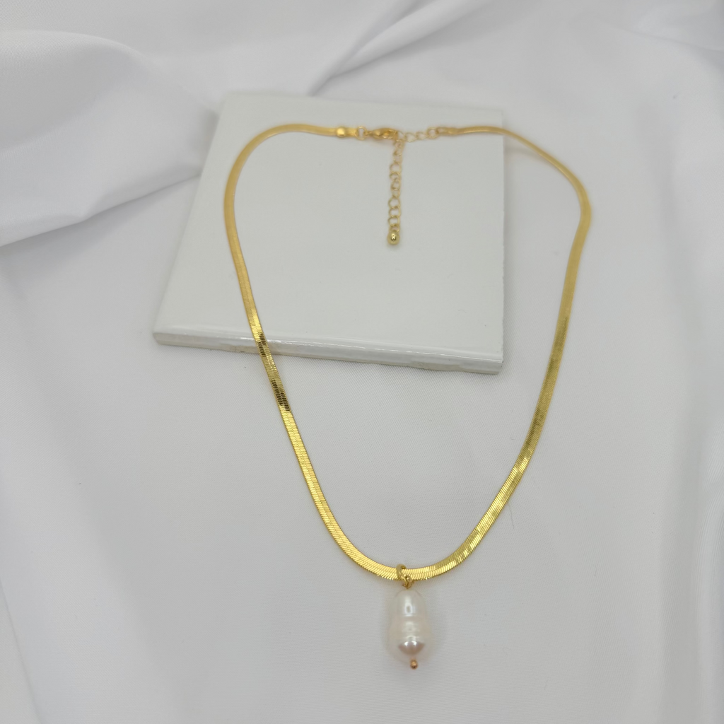 Gold necklace with a pearl pendant on a white fabric background