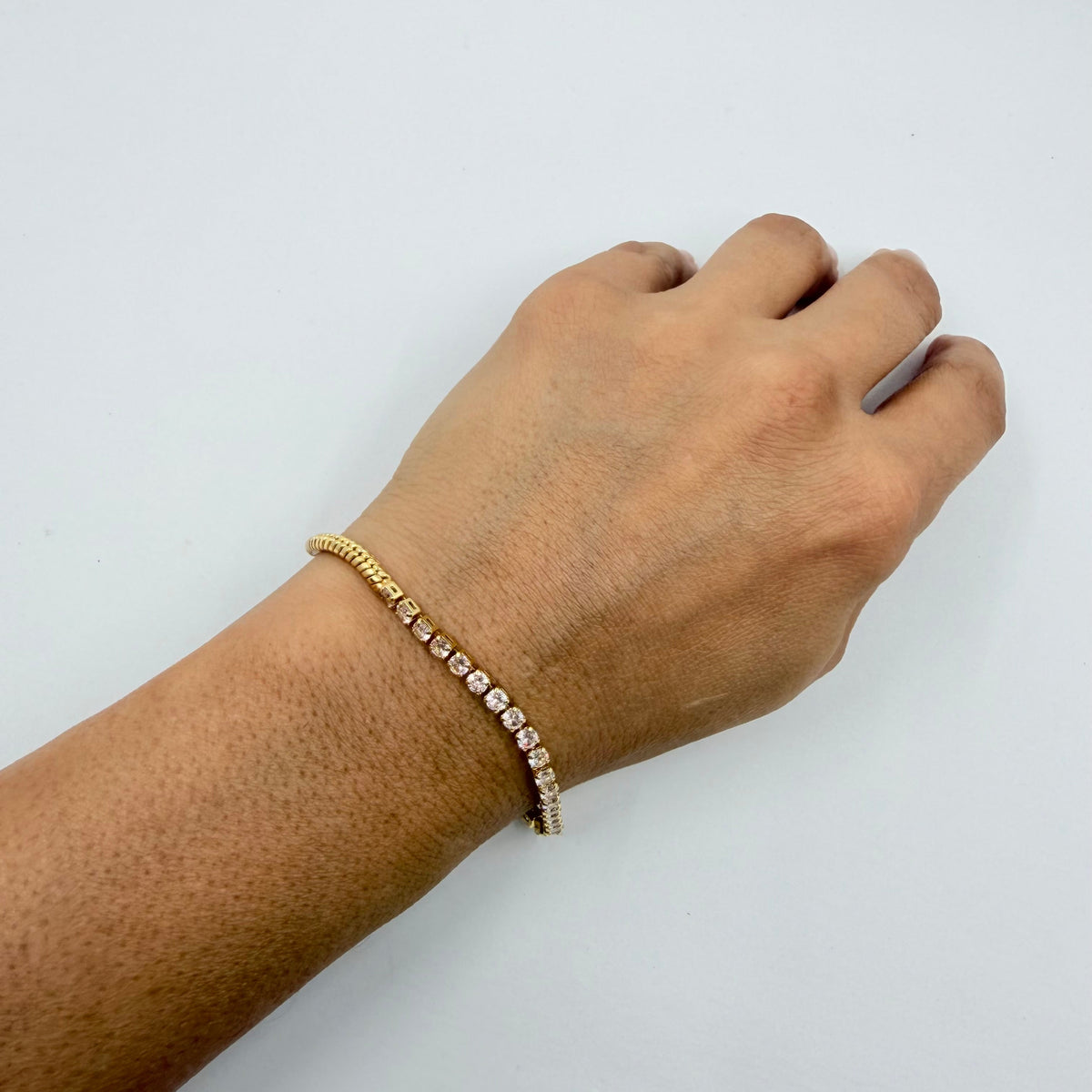 A gold tennis bracelet with clear stones  