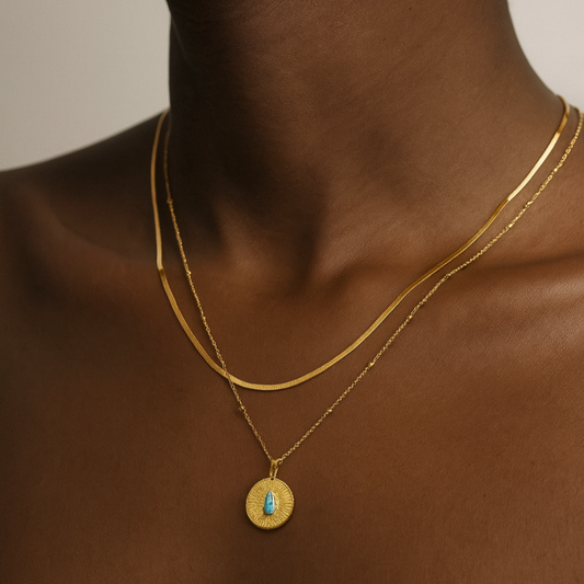 Gold necklace with a pendant on a person against a neutral background