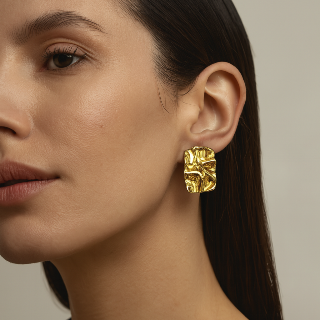 Close-up of a woman wearing gold earrings with a neutral background