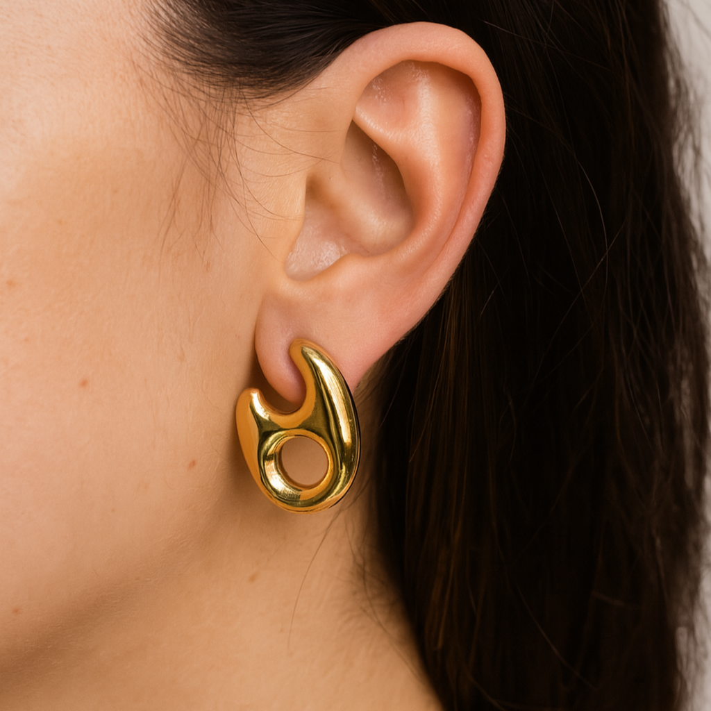 Gold hoop earring worn by a person with dark hair.
