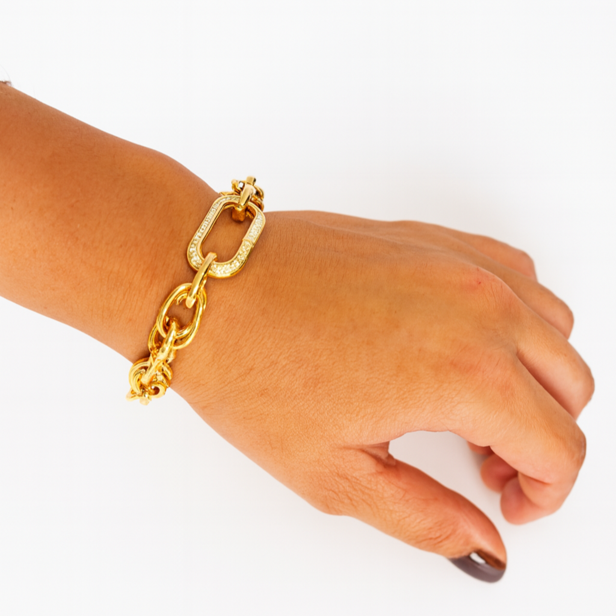 Gold chain bracelet on a wrist against a white background