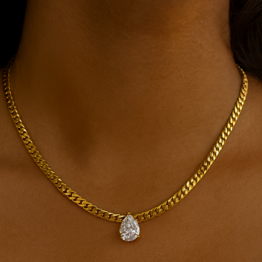Gold chain necklace with a teardrop pendant on a person's neck