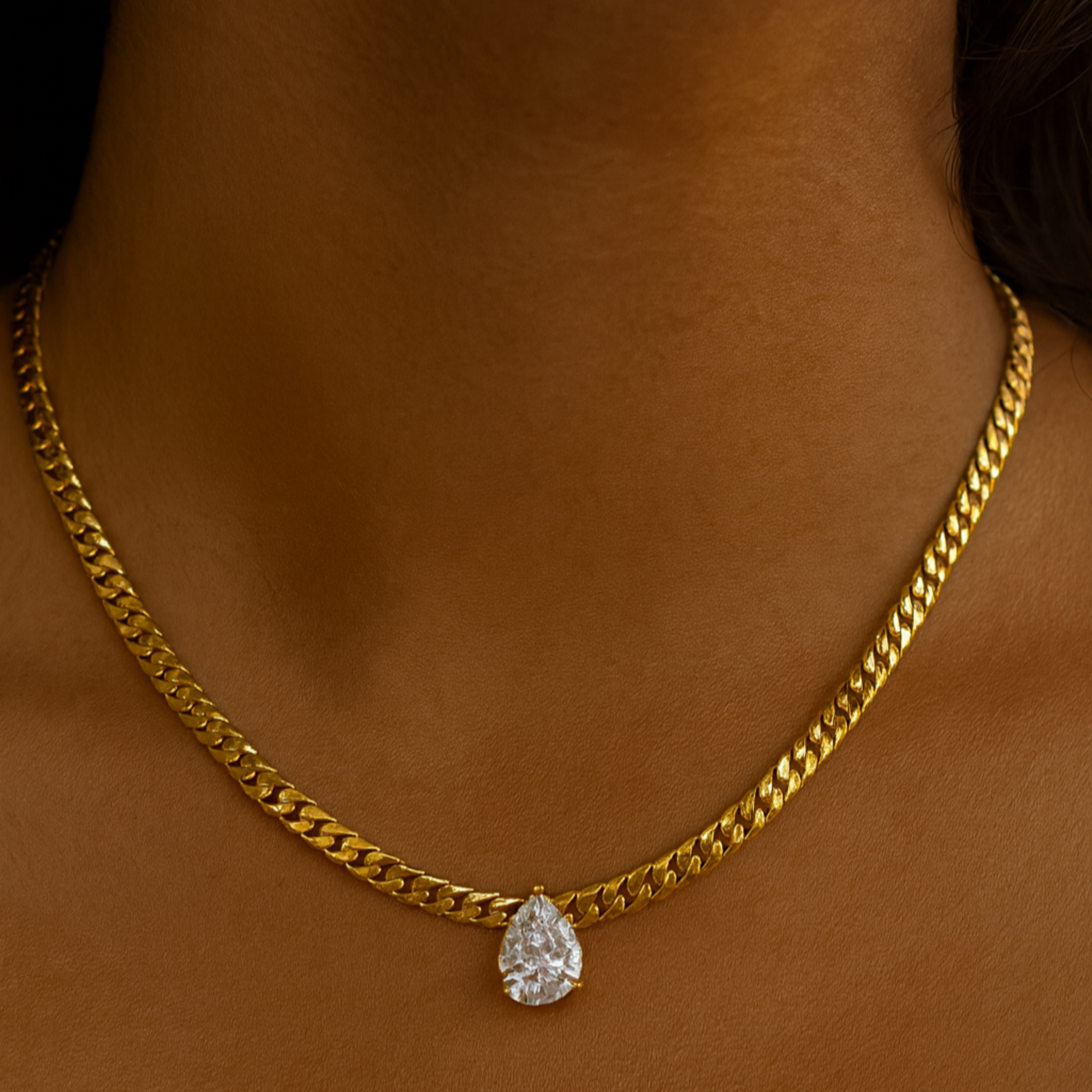 Gold chain necklace with a teardrop pendant on a person's neck