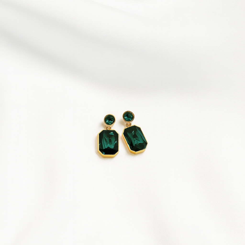 Gold earrings with green gemstones on a white background