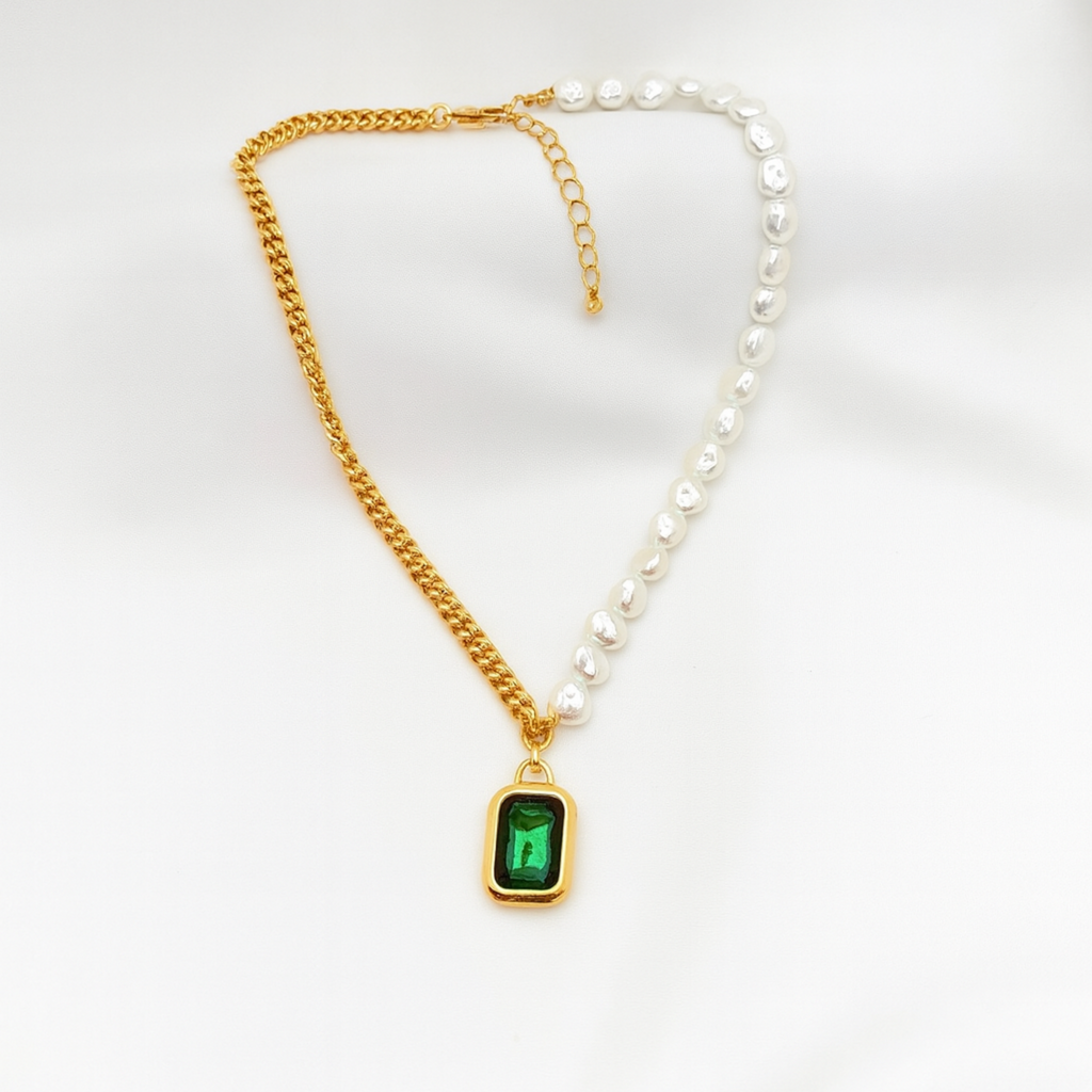 Gold chain necklace with a green pendant and white pearl necklace on a white background