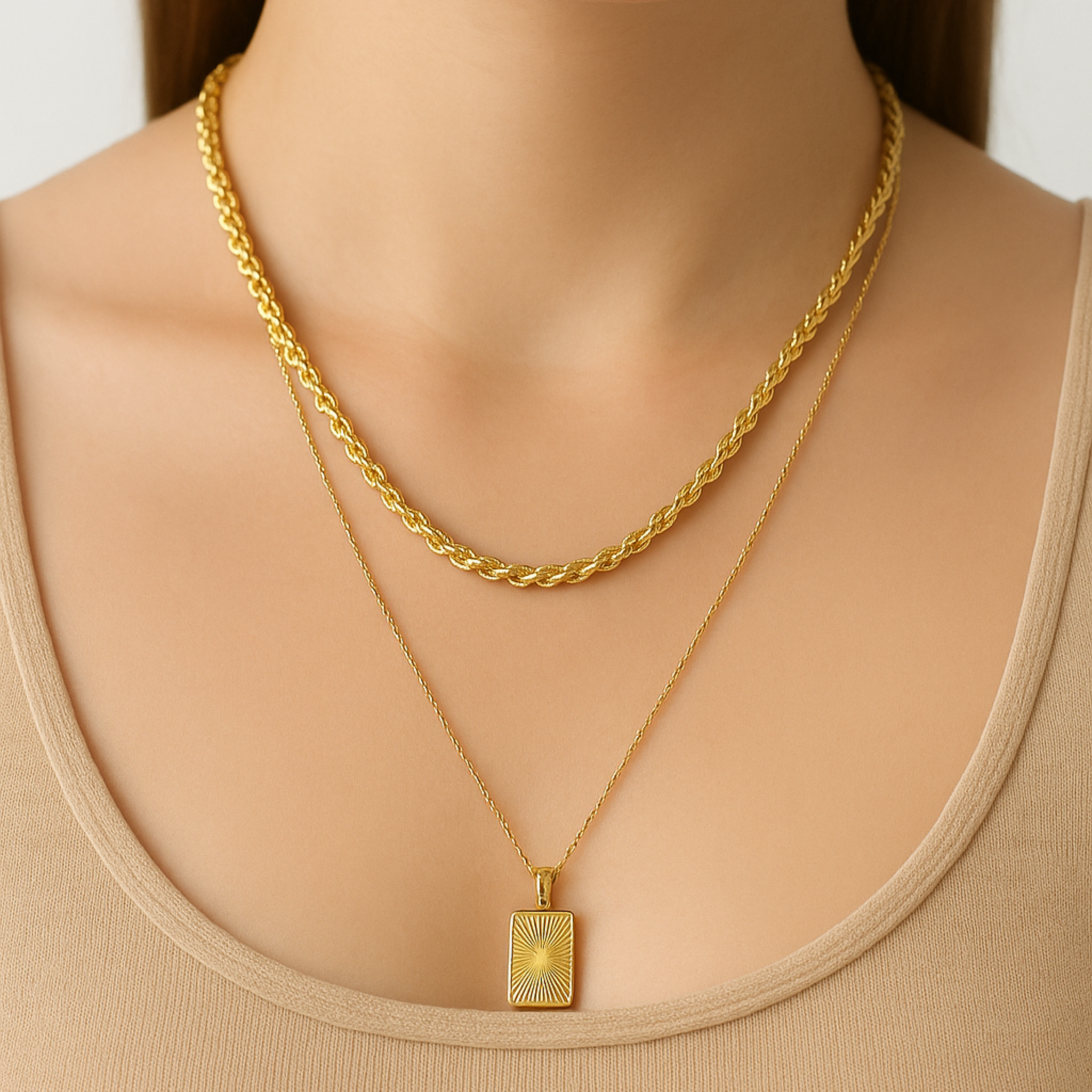 Gold necklace with a pendant worn by a person against a neutral background