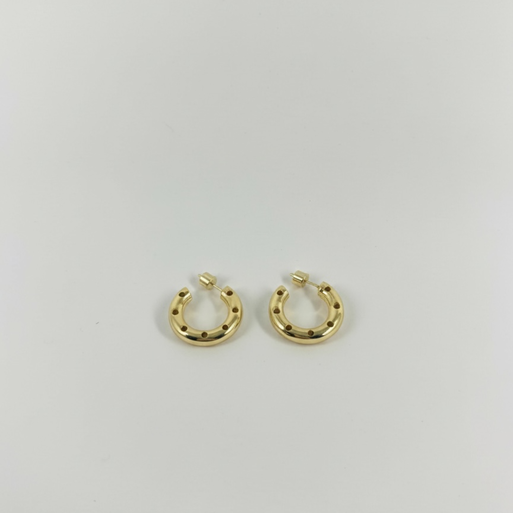 Gold horseshoe-shaped earrings on a light gray background