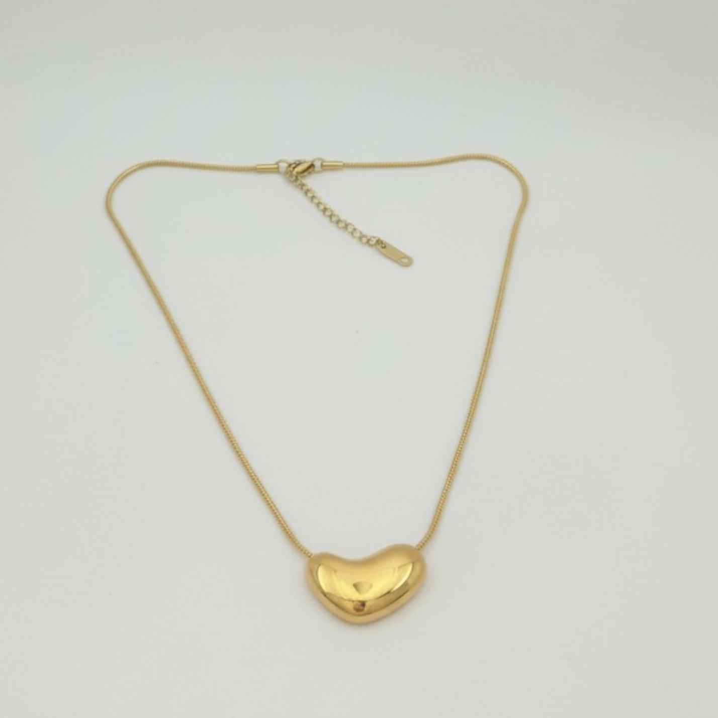 Gold heart-shaped pendant necklace on a light gray background