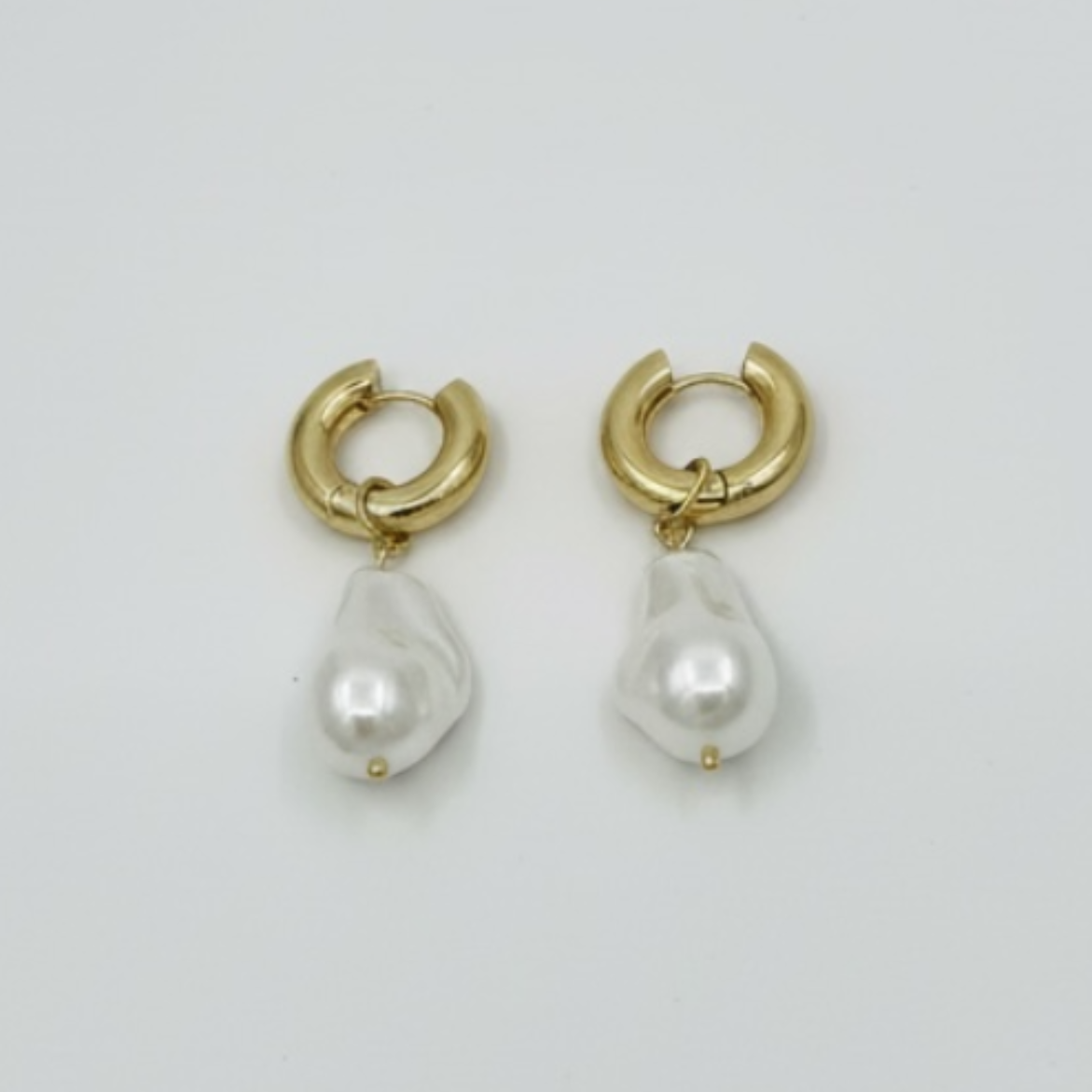 Gold hoop earrings with teardrop-shaped pearls on a light gray background