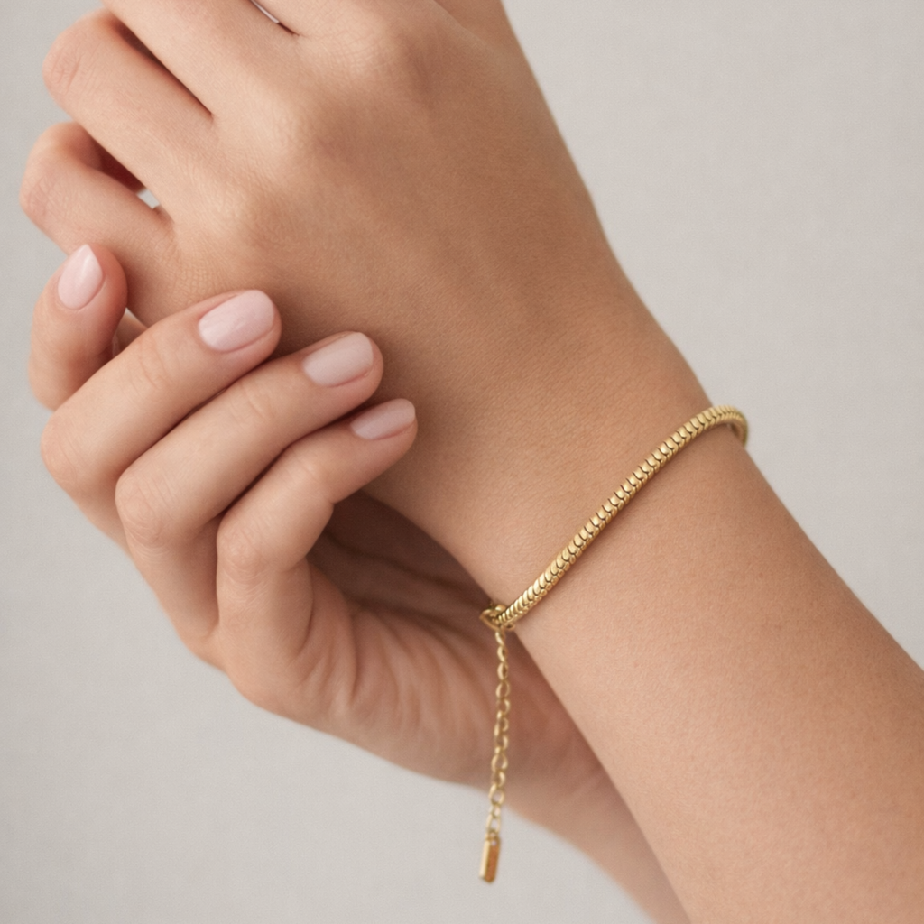 Gold bracelet on a person's wrist with a neutral background