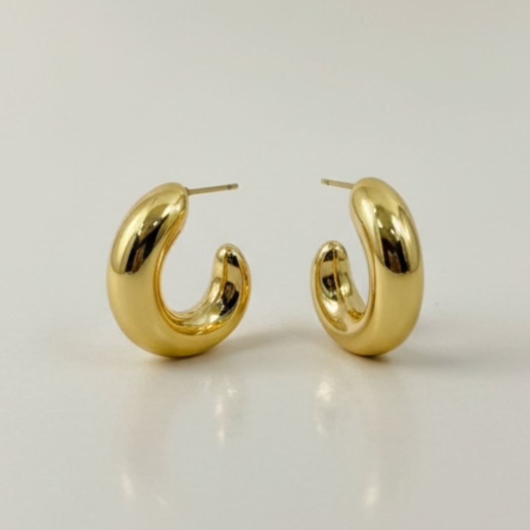 Gold hoop earrings on a light beige background