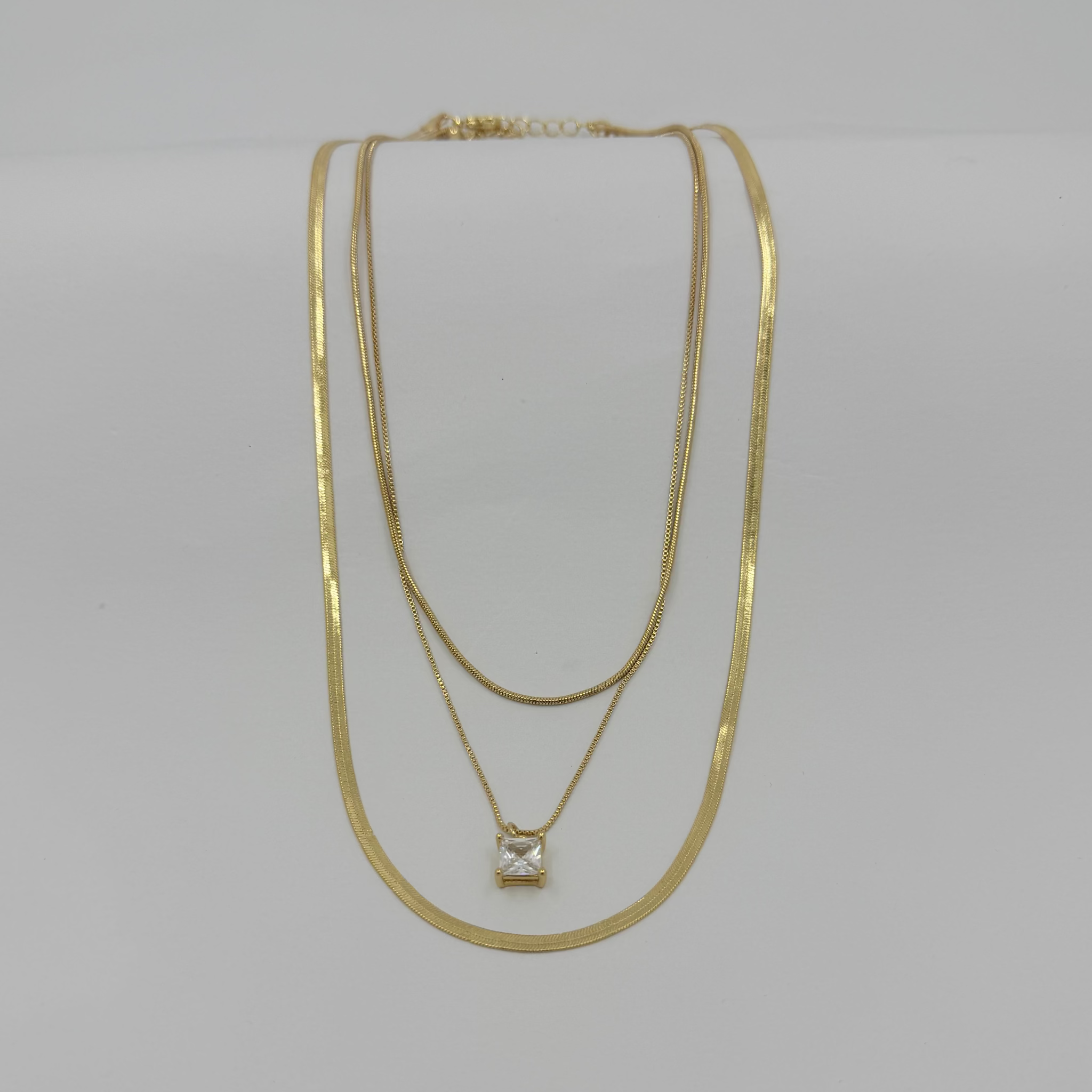 Two gold necklaces on a light gray background