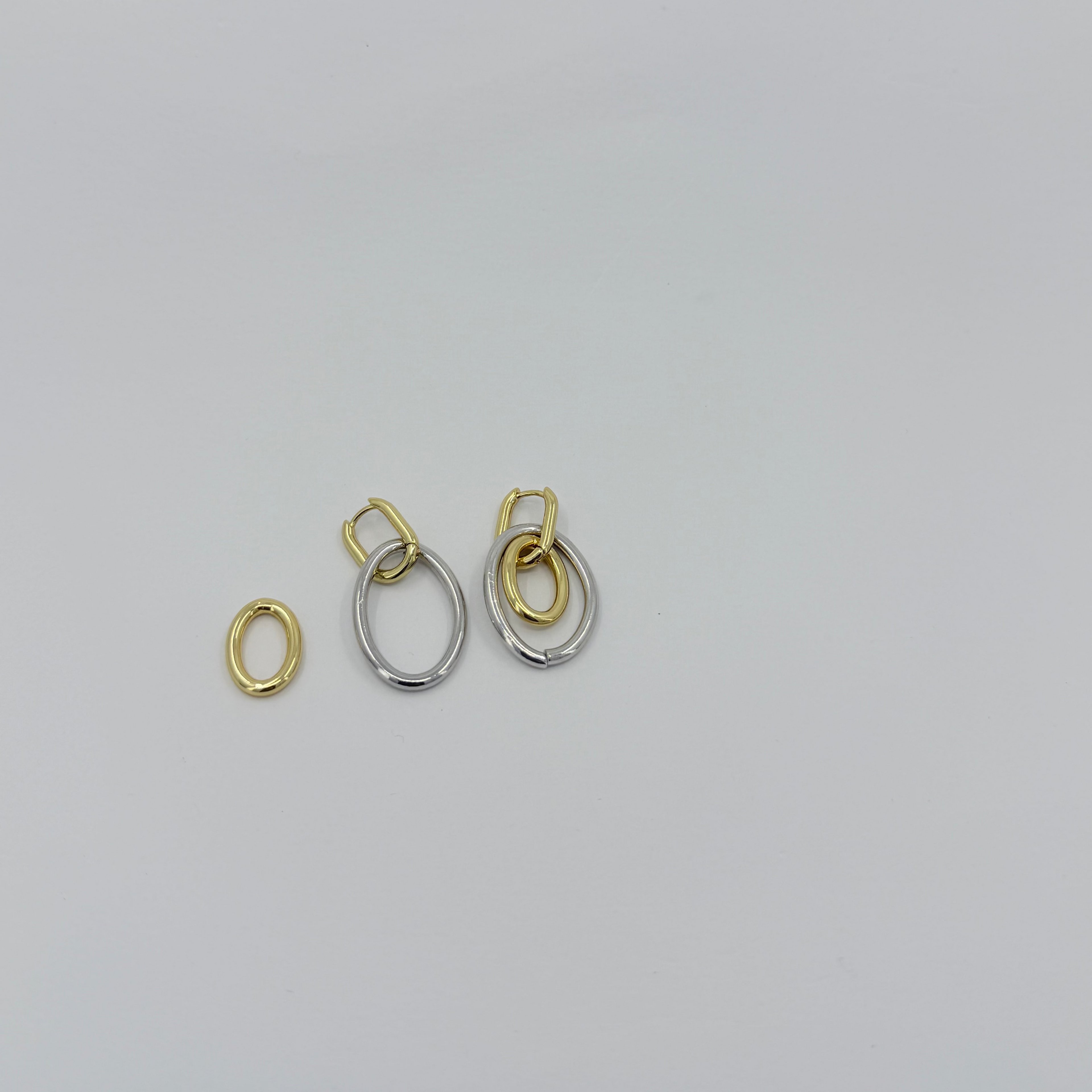 Two gold and silver earrings on a light gray background