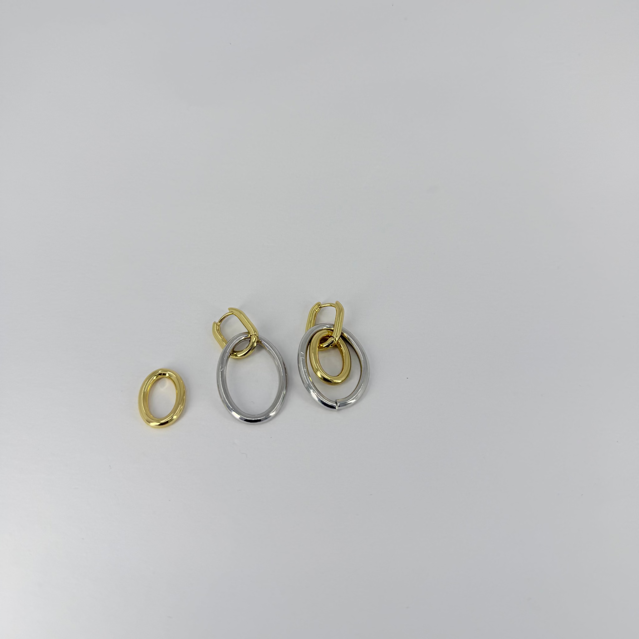 Two pairs of gold and silver earrings on a light gray background