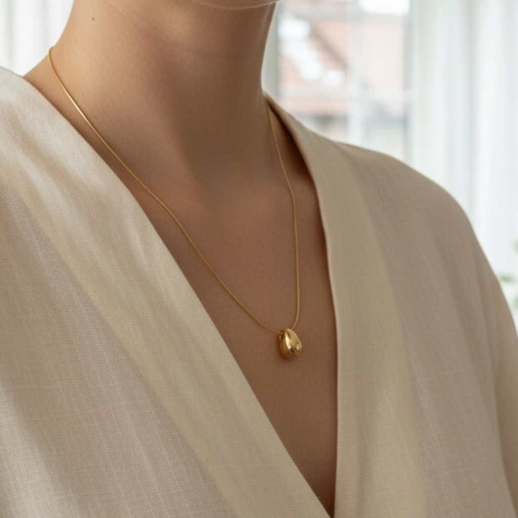 Woman wearing a gold necklace in a blurred indoor setting