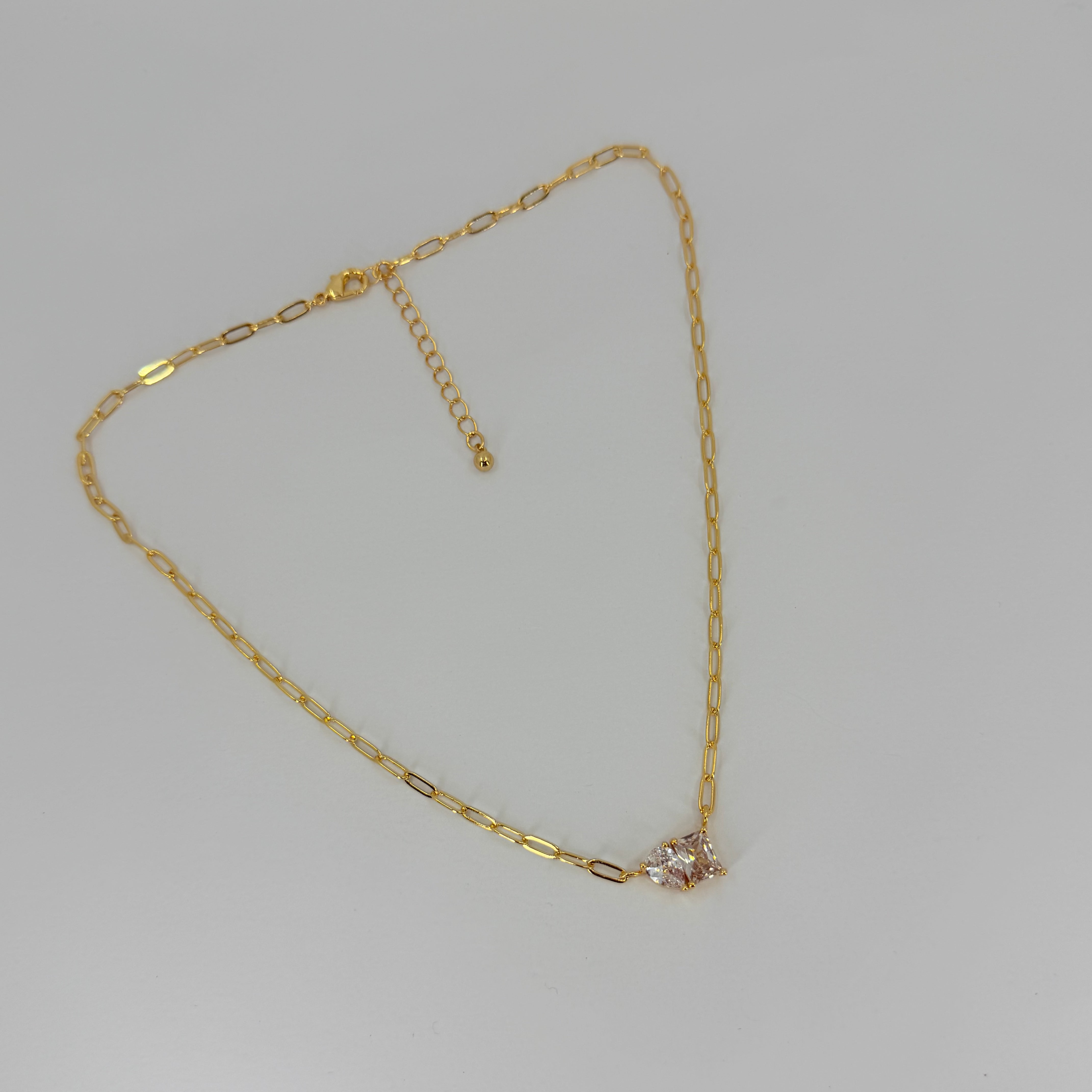 Gold necklace with a small diamond pendant on a light gray background
