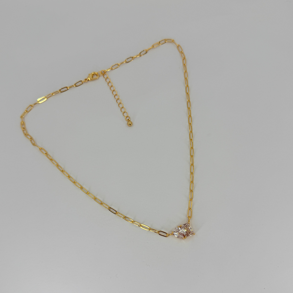 Gold necklace with a small diamond pendant on a light gray background